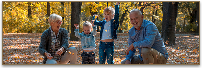 Grandparents playing in the leaves with their grand children